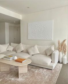 a living room filled with white furniture and pillows on top of a carpeted floor