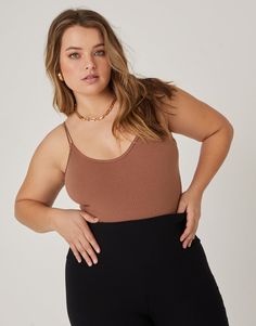 a woman in black pants and a brown tank top is posing with her hands on her hips