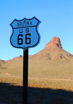 a blue highway sign sitting in the middle of a desert area next to a mountain