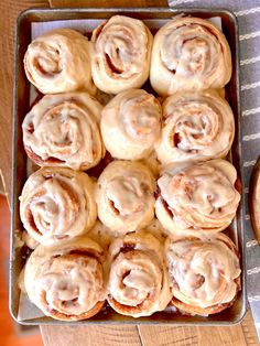 a pan filled with cinnamon rolls on top of a wooden table