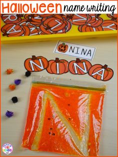 an orange bag filled with candy next to a halloween name writing activity on a table