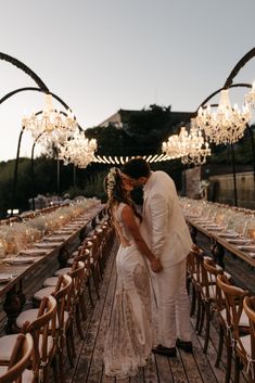 a bride and groom kissing in front of an outdoor dining area with chandeliers