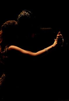 two people are dancing together in the dark