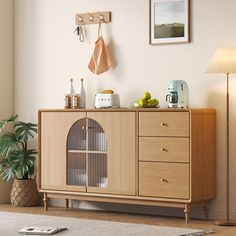 a living room with a large wooden cabinet next to a lamp and pictures on the wall