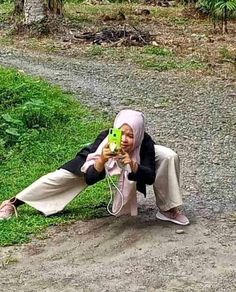 a woman sitting on the ground while holding a cell phone