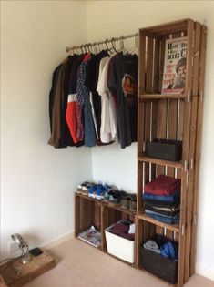 a closet with clothes hanging on the wall and baskets below it, in front of a white wall