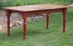 a wooden table sitting on top of a lush green grass covered field next to rocks