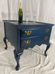 a blue table with two wine glasses on it and a bottle in the top drawer