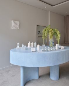 a blue table with candles on it and a potted plant in the middle is shown