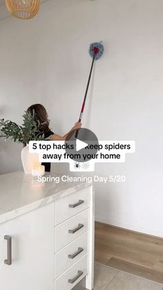 a woman is cleaning the kitchen counter with a mop and bucket full of plants