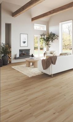 a living room with white furniture and wood flooring in front of a fire place