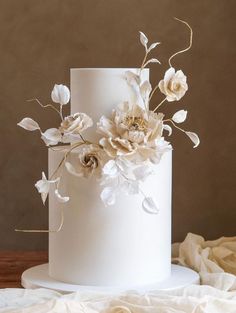 there is a white cake with flowers on the top and bottom tier, sitting on a table