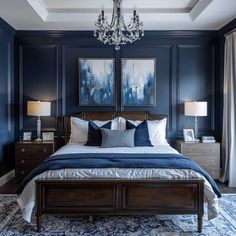 a bedroom with blue walls and white bedding, chandelier and two paintings on the wall