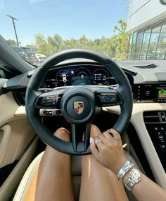 a woman is sitting in the driver's seat of a car with her hands on the steering wheel