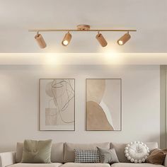 a living room with two couches and three lamps on the ceiling above each sofa