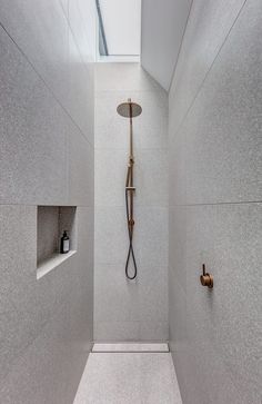 a walk in shower sitting next to a white tiled wall and ceiling with a skylight above it