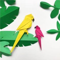 two paper birds sitting on top of green leaves