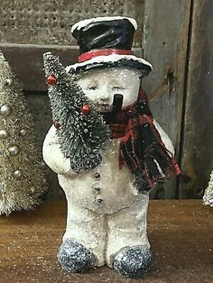 a snowman figurine with a christmas tree in his hat on a table