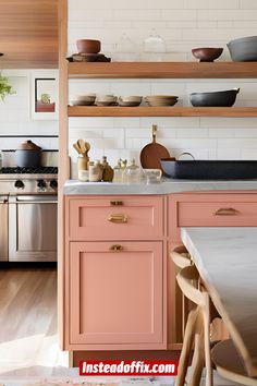 a kitchen with pink cabinets and wooden shelves