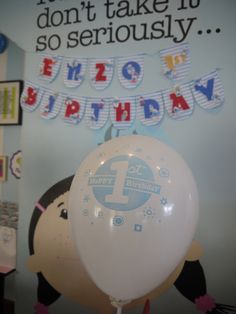 a white balloon sitting on top of a table next to a sign that says happy birthday