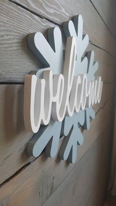 a welcome sign mounted to the side of a wooden wall with snowflakes on it