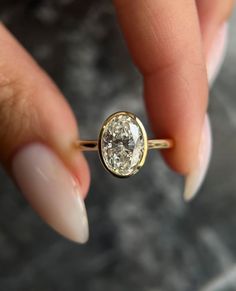 a woman's hand holding an engagement ring with a diamond in the middle, on top of her finger