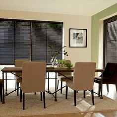 a dining room table and chairs with blinds on the windows