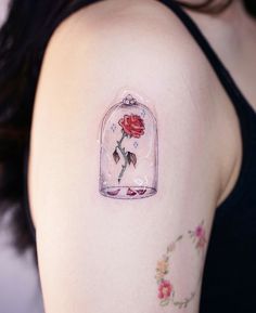 a woman with a tattoo on her arm has a red rose in a glass jar