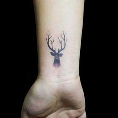 a small deer head tattoo on the wrist