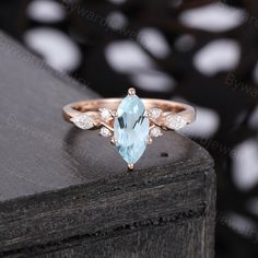 an aqua blue topazte and diamond ring on a wooden surface with white dots in the background