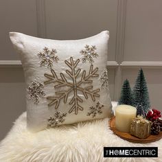 a white pillow with a snowflake design on it sitting next to a candle