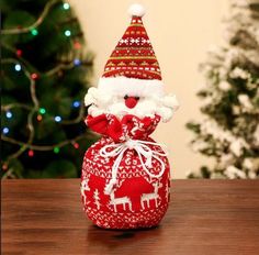 a red and white knitted santa clause sitting on top of a wooden table