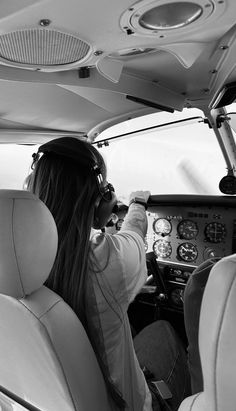 two people are sitting in the cockpit of an airplane and one person is wearing headphones