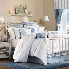 a bed with blue and white comforters in a room next to a large window