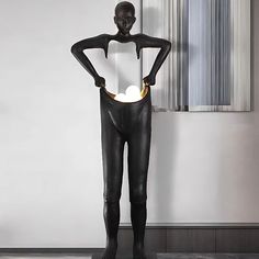 a black mannequin standing in front of a white wall with a light on it's back