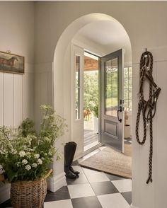 a hallway with a checkered floor and an archway leading to the front door is shown