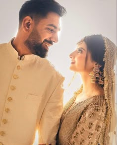 a man and woman standing next to each other in front of a sunlit background