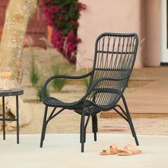 a black wicker chair sitting on top of a white rug next to a table