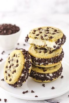 chocolate chip ice cream sandwich cookies on a white plate next to a bowl of chocolate chips