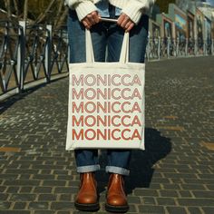 a woman holding a bag with the words monica monica written on it in red and white