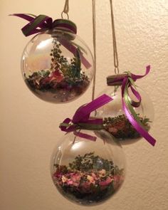 two glass ornaments with flowers and ribbons hanging from the ceiling