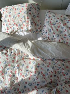 an unmade bed with white sheets and colorful flowers