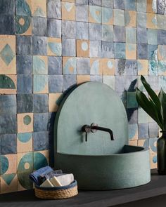 a bathroom sink sitting on top of a counter next to a vase and potted plant