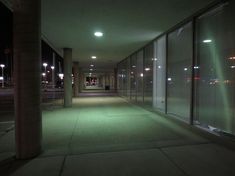 an empty hallway with large windows and lights on either side of the building at night