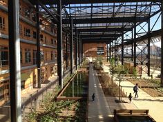 people are walking around in an open area with water and plants on either side of the walkway