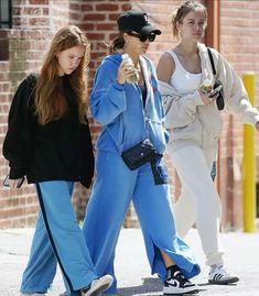 three young women walking down the street with one holding a cell phone in her hand