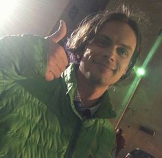 a man in a green jacket giving the thumbs up