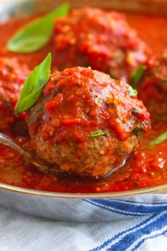 meatballs with tomato sauce in a bowl on a blue and white towel, ready to be eaten