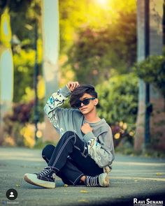 a young man sitting on the ground with his hands behind his head and wearing sunglasses