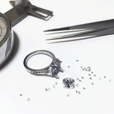 a pair of scissors and a ring on a table with some diamonds next to it